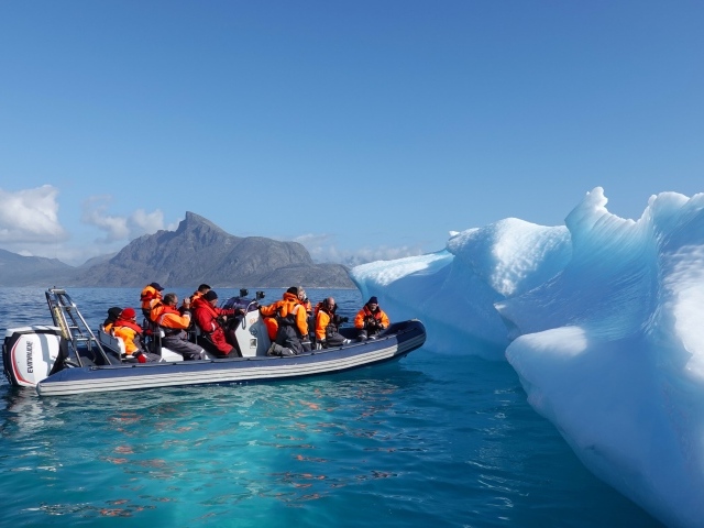Группа туристов на лодке у айсберга