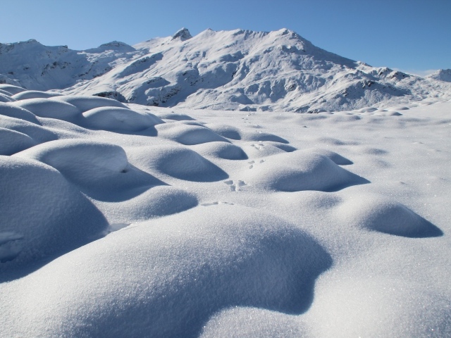 Заснеженные камни на поверхности горы в лучах солнца