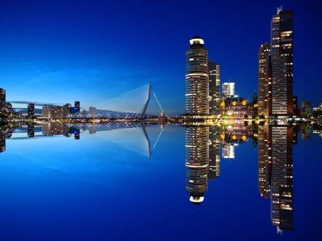 Небоскребы и мост отражаются в тихой воде