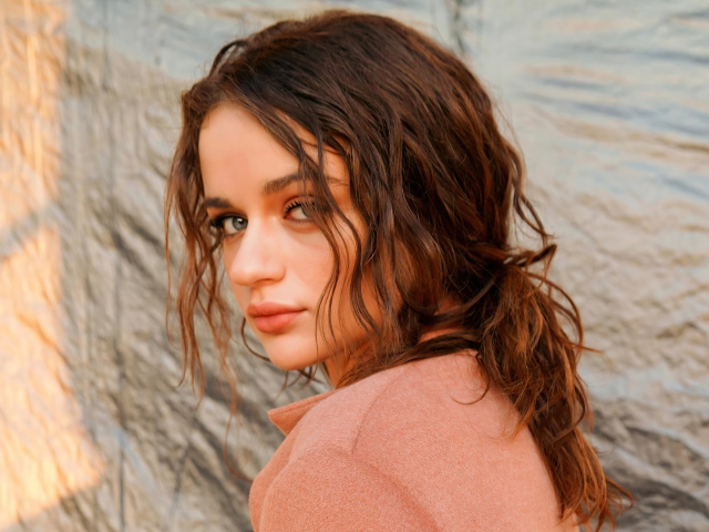 Актриса Джои Кинг стоит боком у стены 