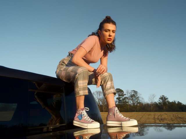 Актриса Милли Бобби Браун сидит на машине в кедах