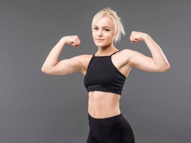 Красивая стройная спортивная девушка показывает мускулы