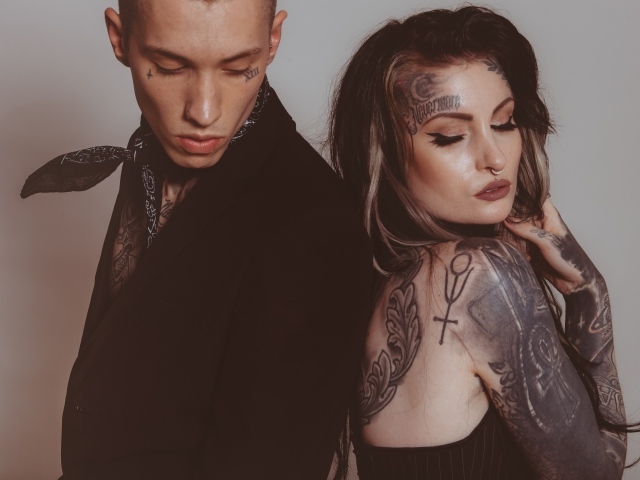 Девушка и парень с татуировками на теле на сером фоне