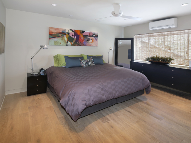 Большая серая кровать в спальне с белыми стенами