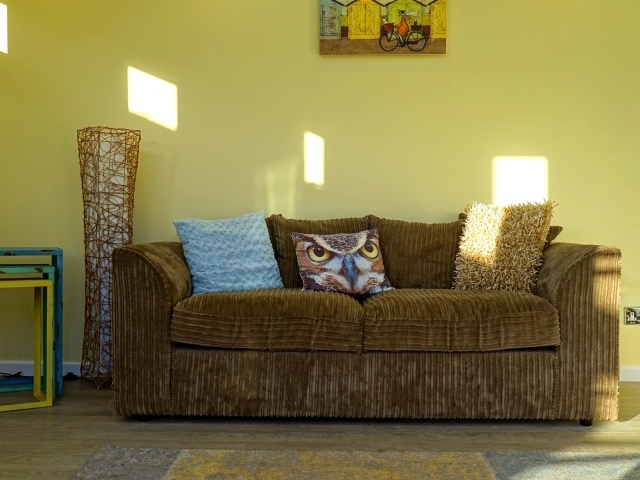Большой старый диван в комнате с желтыми стенами