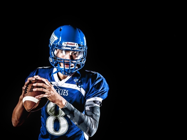 Мужчина игрок в американский футбол на черном фоне