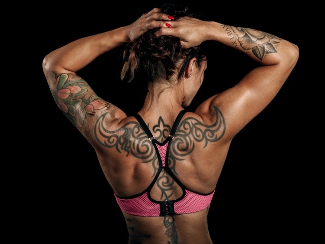 Татуировки на теле спортивной девушки на черном фоне