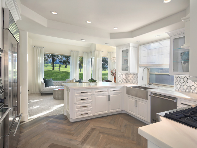 Белый кухонный гарнитур в комнате с большим окном