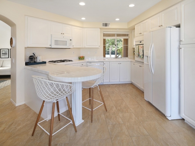 Белая стильная мебель с большим холодильником на кухне