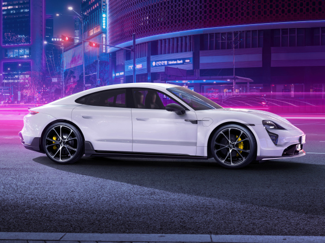 Белый автомобиль Porsche Taycan Aerokit 2021 года в мегаполисе