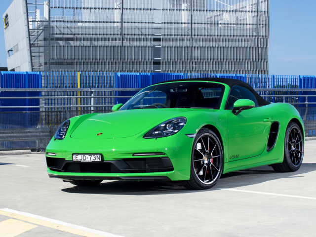 Зеленый автомобиль Porsche 718 Boxster GTS у здания 