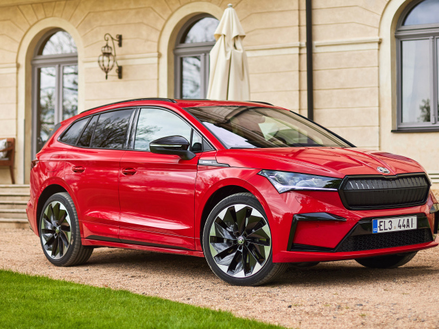 Красный автомобиль Skoda Enyaq Sportline IV 2021 года у стены