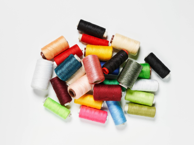 Много катушек разноцветных ниток на белом фоне 