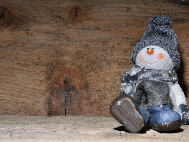 Фигурка снеговик у деревянной стены