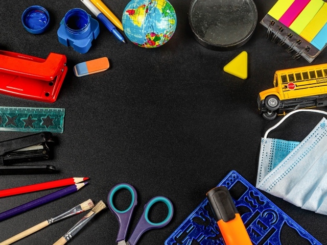 Канцелярские предметы, игрушки и маска на черном столе 