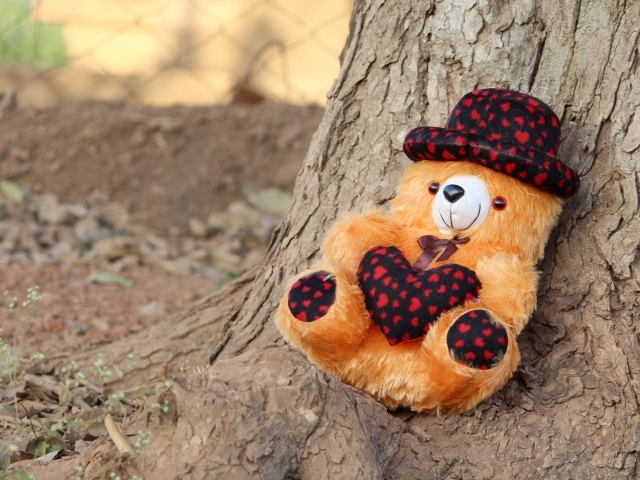 Медвежонок Тедди лежит под деревом