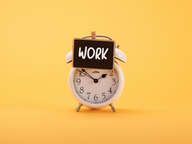 Белый будильник с табличкой на желтом фоне