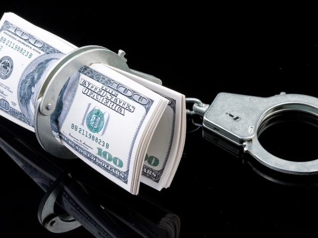 Пачка долларов с наручниками на черном фоне