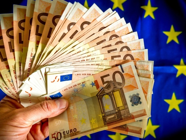 Пачка евро в руке на фоне флага
