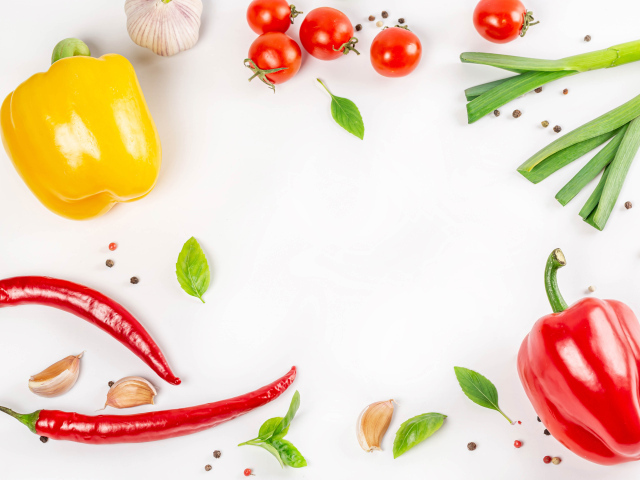 Разный перец на белом фоне с чесноком и помидорами