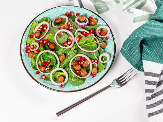 Вегетарианский салат с листьями базилика, орехами, зернами граната и луком