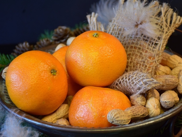 Желтые апельсины с арахисом  на тарелке