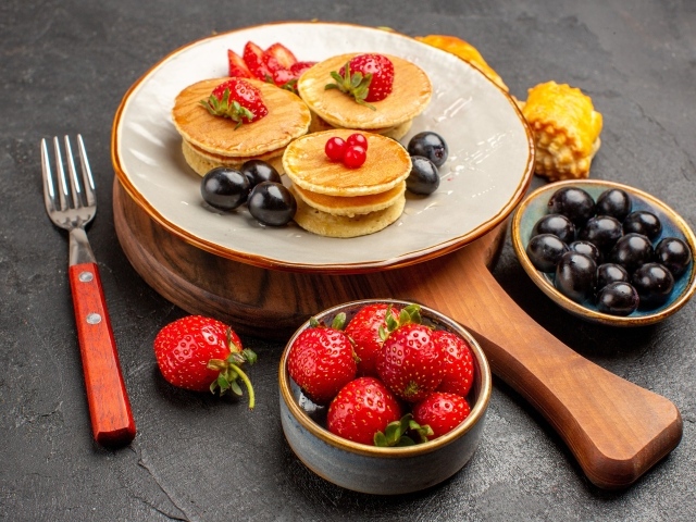 Оладьи с виноградом и клубникой на тарелке 