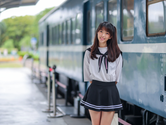 Красивая девушка азиатка в костюме стоит у поезда