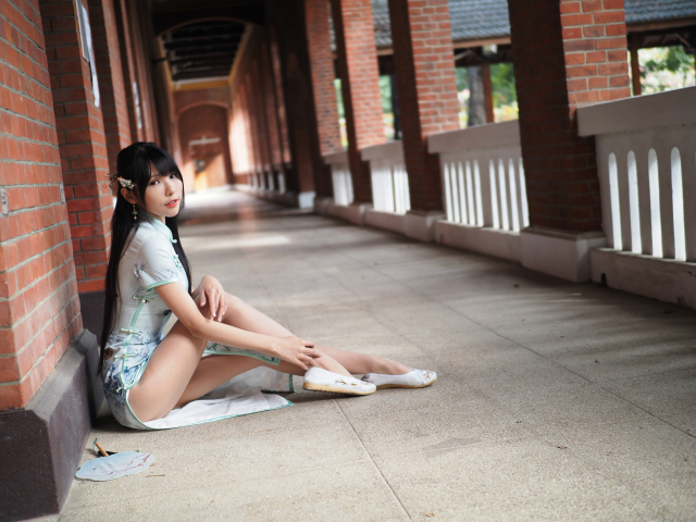 Девушка азиатка сидит на холодном полу у стены