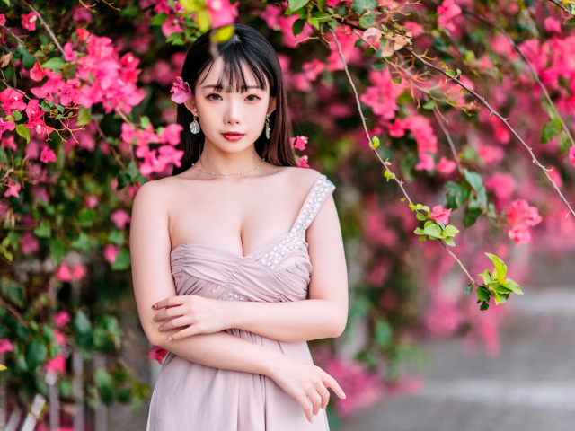 Красивая девушка азиатка у куста с  красными цветами 