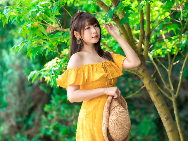 Красивая девушка азиатка в желтом платье у дерева 