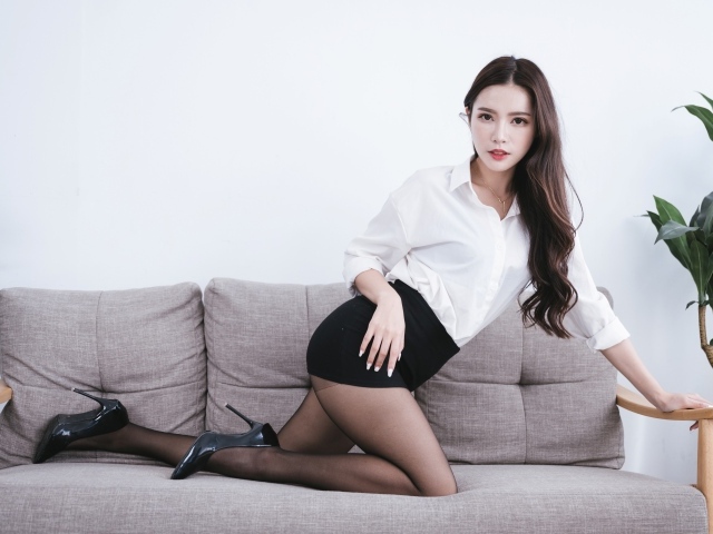 Красивая азиатка в белой рубашке на диване