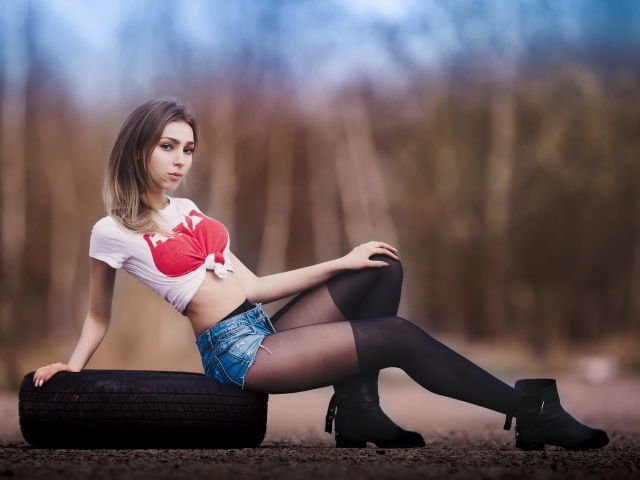 Красивая девушка в чулках сидит на покрышке 