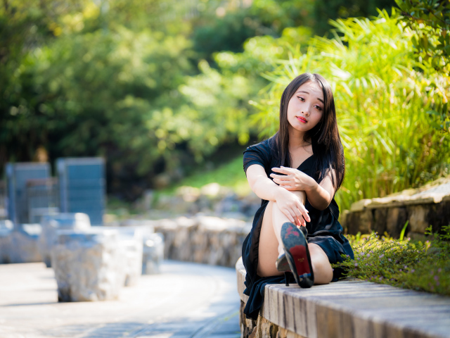 Грустная девушка в черном платье отдыхает в парке