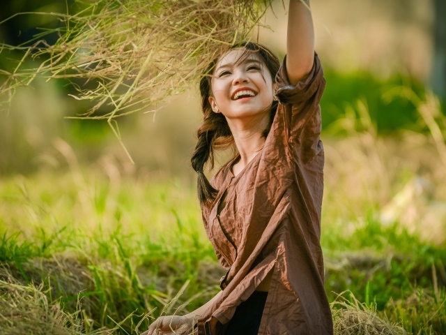 Улыбающаяся девушка азиатка с травой в руках 