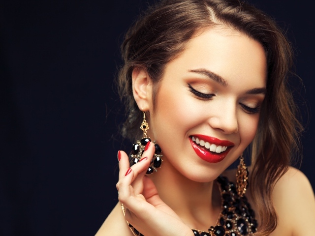 Улыбающаяся девушка носит украшения с черными камнями