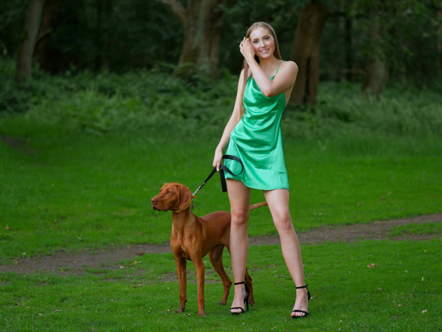 Молодая девушка гуляет с собакой в парке