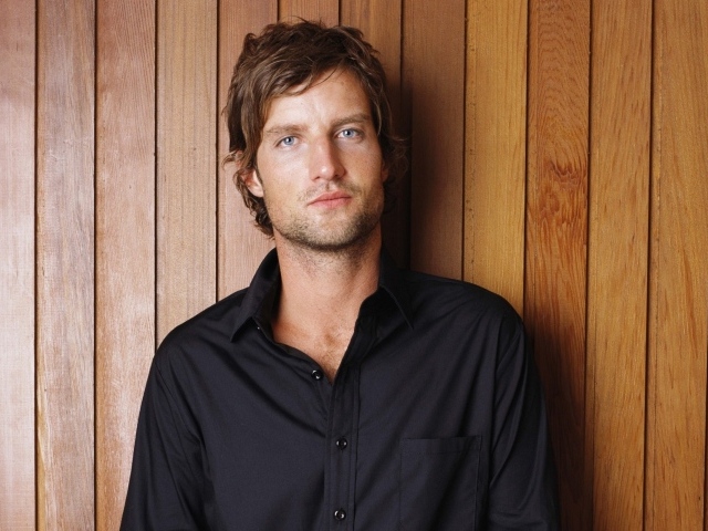 Красивый мужчина в черной рубашке на деревянном фоне