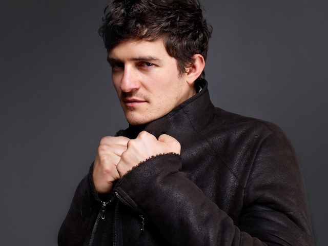 Красивый актер Орландо Блум на сером фоне