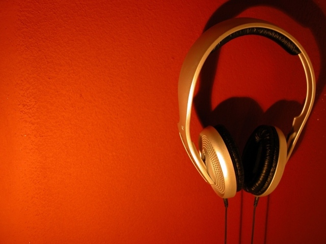 Большие золотые наушники на оранжевом фоне 
