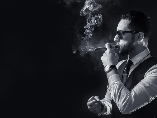 Мужчина с сигарой в руке на черном фоне 