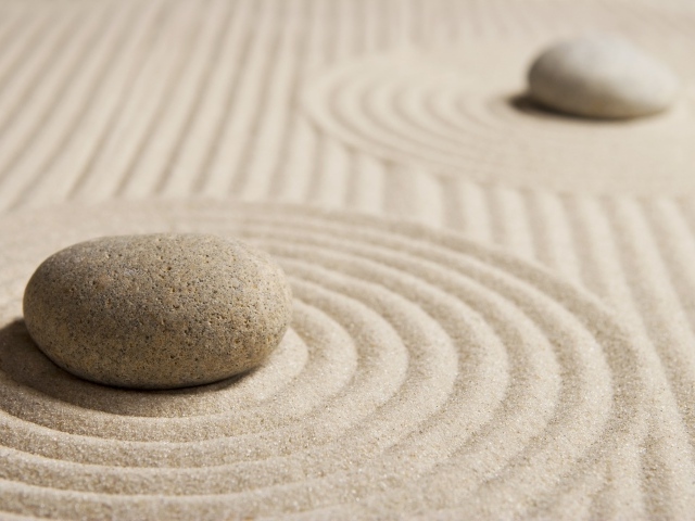 Большой серый камень на песке с кругами 