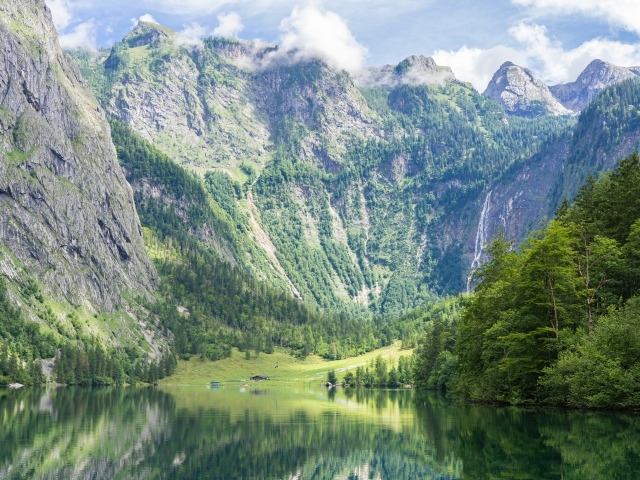 Высокие горы у озера с зелеными деревьями