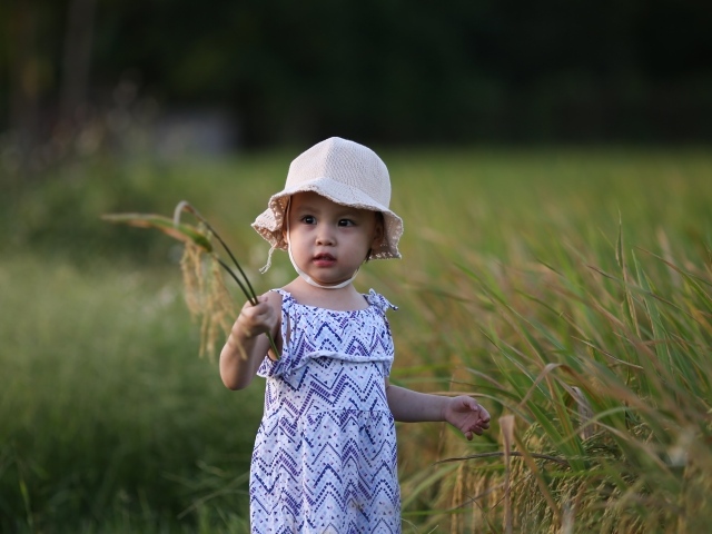 Маленькая девочка азиатка стоит в траве