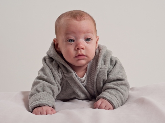 Маленький новорожденный мальчик в сером костюме