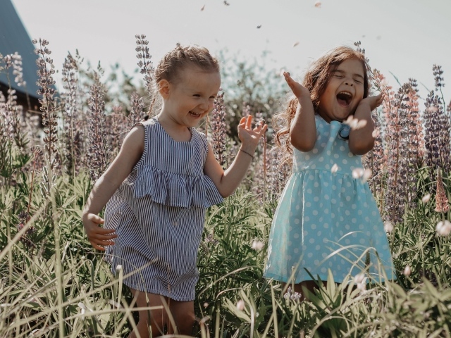 Две маленькие веселые девочки в цветах 