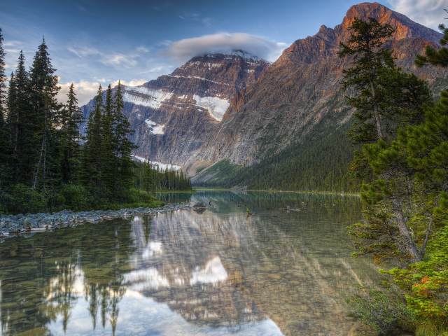 Камни лежат в воде озера у гор, Канада 