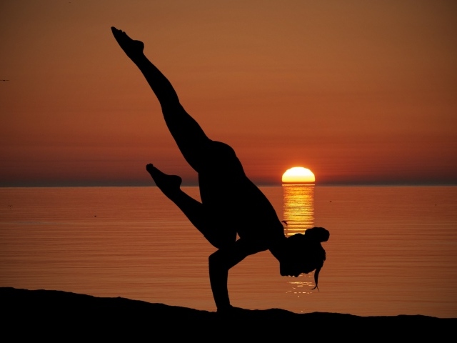 Девушка занимается йогой на закате солнца