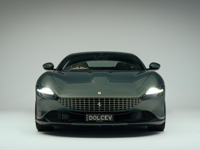 Автомобиль Ferrari Roma на сером фоне вид спереди