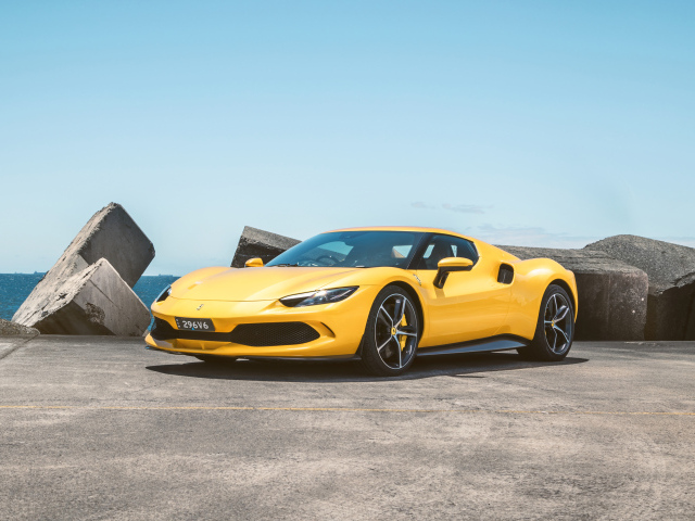 Желтый автомобиль Ferrari 296 GTB у камней